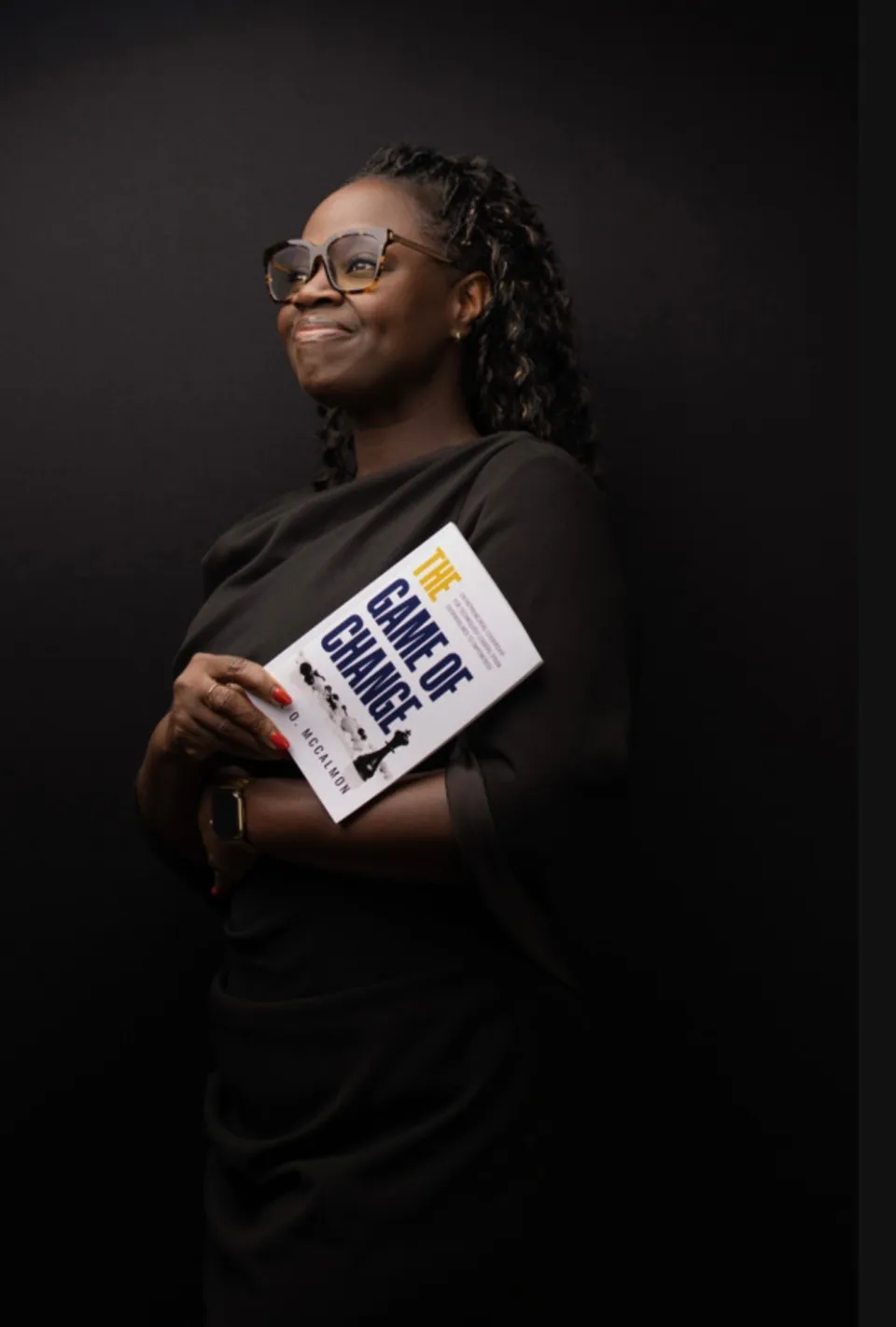 Adie O. McCalmon holding her book in a thoughtful studio portrait